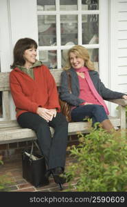 Two mature women sitting on a bench and gossiping