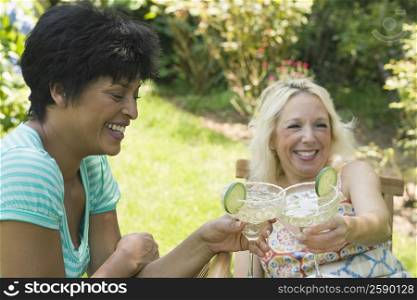 Two mature women toasting with martini glasses