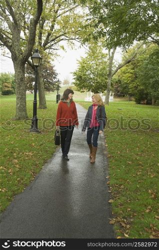 Two mature women walking on a footpath and gossiping