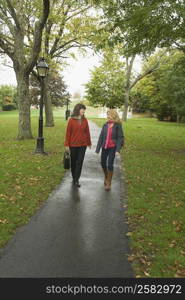 Two mature women walking on a footpath and gossiping