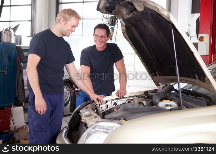 Two mechanics looking at and working on a car in a repair shop