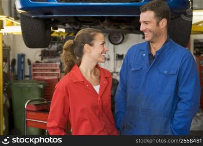 Two mechanics standing in garage smiling