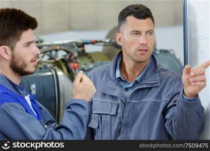 two mechanics working on a small aircraft in a hangar