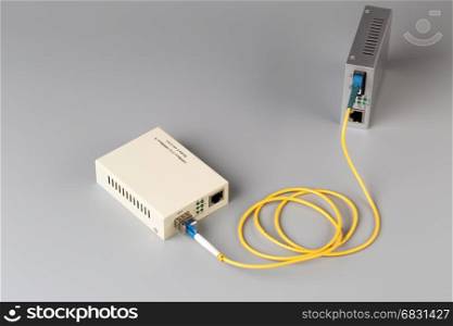 Two media converters connected by fiber cable. Two media converters connected by fiber cable on grey background