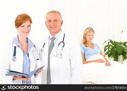 Two medical doctors professional with hospital patient lying in bed