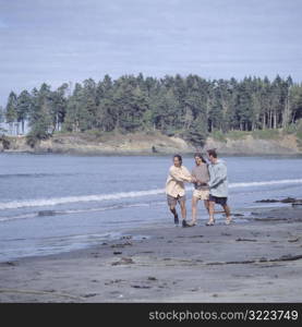 Two Men And A Woman Playing On The Beach