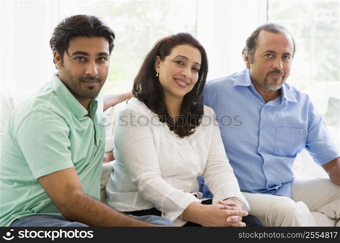 Two men and a woman sitting in living room smiling (high key)