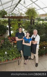 Two men and a woman standing with their arms crossed in a garden center