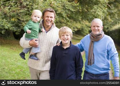 Two men and two young children standing on path outdoors smiling (selective focus)