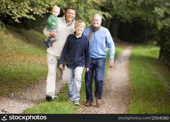 Two men and two young children walking on path outdoors smiling (selective focus)