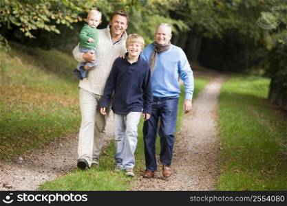 Two men and two young children walking on path outdoors smiling (selective focus)