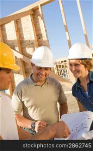Two men and woman with blueprints at construction site, portrait