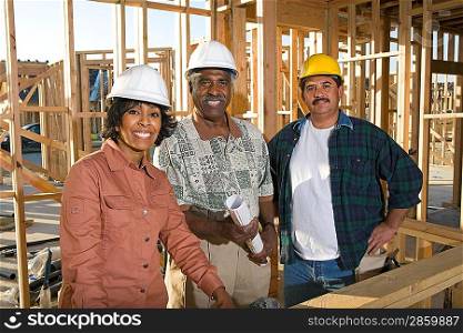Two men and women with blueprints at construction site, portrait
