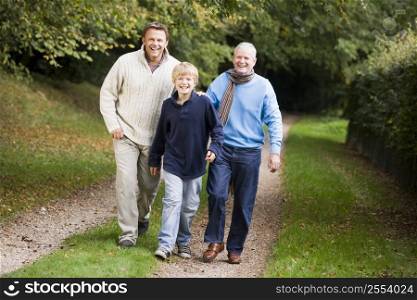 Two men and young boy walking on path outdoors smiling (selective focus)
