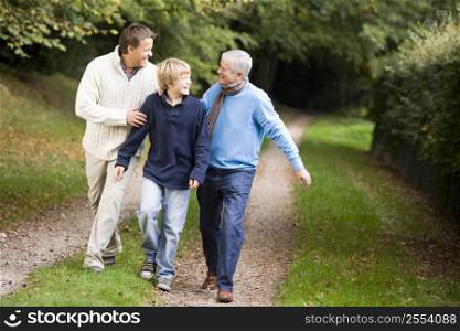 Two men and young boy walking on path outdoors smiling (selective focus)