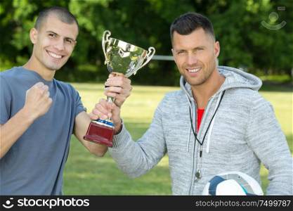 two men are holding a trophy