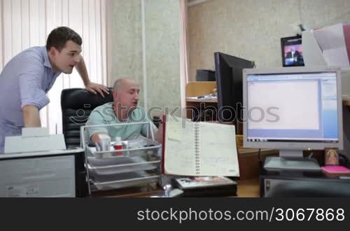 Two men are working at the computer in the office