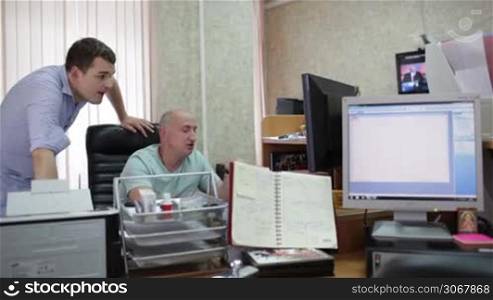 Two men are working at the computer in the office