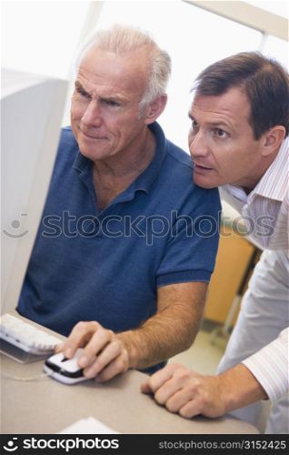 Two men at computer looking at monitor (high key)