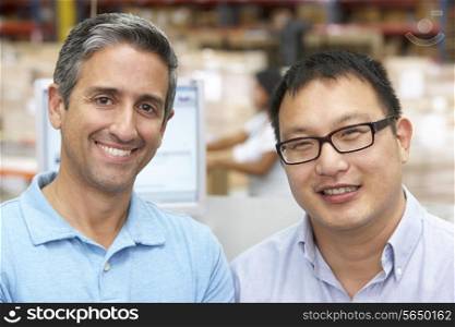 Two Men At Computer Terminal In Distribution Warehouse