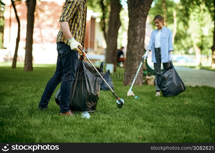 Two men collects plastic garbage in bags in park, volunteering. Male person cleans forest, ecological restoration, eco lifestyle, trash collection and recycling, ecology care, environment cleaning. Two men collects plastic garbage, volunteering