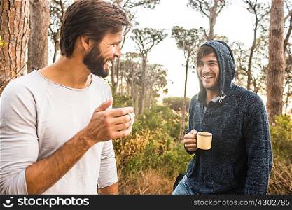 Two men drinking coffee and chatting in forest, Deer Park, Cape Town, South Africa