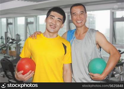 Two men holding balls in the gym