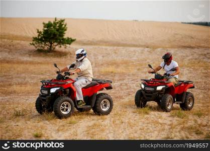 Two men in helmets, freedom atv riding in desert sands. Male persons on quad bikes, sandy race, dune safari in hot sunny day, 4x4 extreme adventure, quad-biking concept. Two men in helmets, atv riding in desert sands