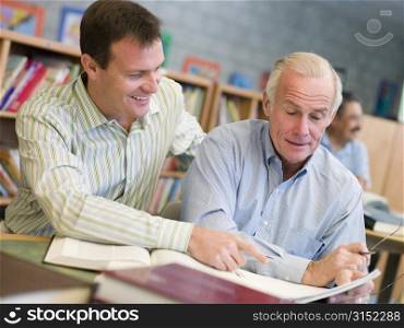 Two men in library talking (selective focus)
