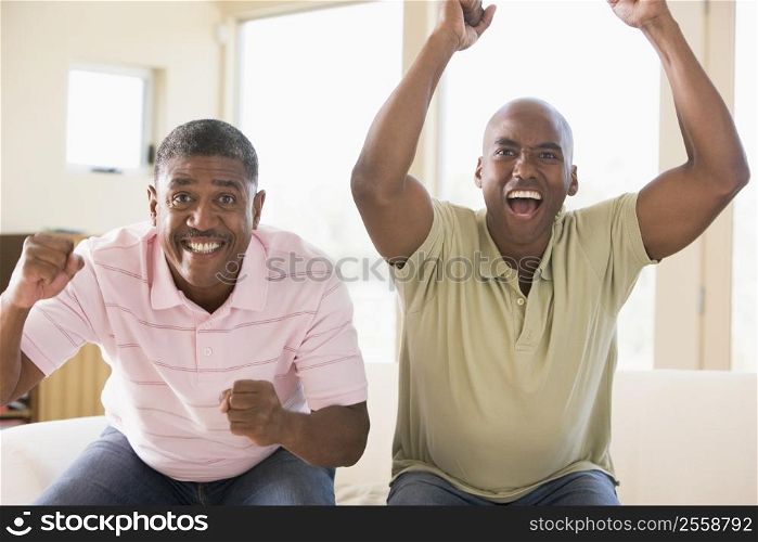 Two men in living room cheering and smiling