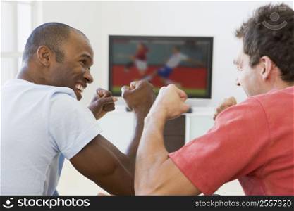 Two men in living room watching television and cheering