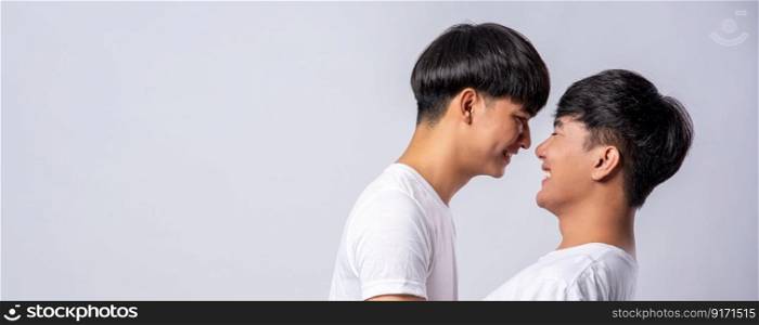 Two men in love wearing white t-shirts looked at each other&rsquo;s faces.