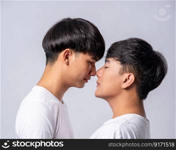 Two men in love wearing white t-shirts looked at each other&rsquo;s faces.
