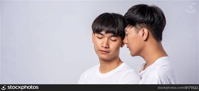 Two men in love wearing white t-shirts looked at each other’s faces.