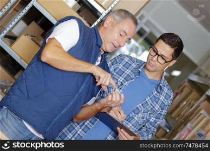 Two men in stores looking at object held in palm of hand