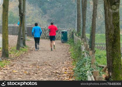 Two men jogging in park in autumn. Health and fitness