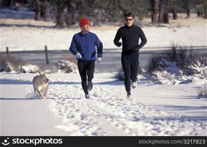 Two Men Jogging in the Snow with a Dog