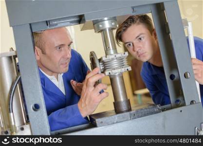 Two men looking at cylinder in vertical clamp