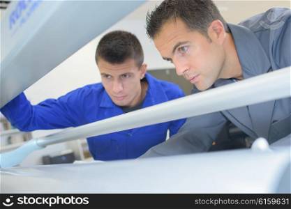 Two men looking into printing machine