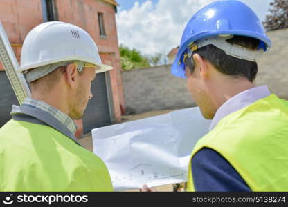 Two men on building site looking at plans