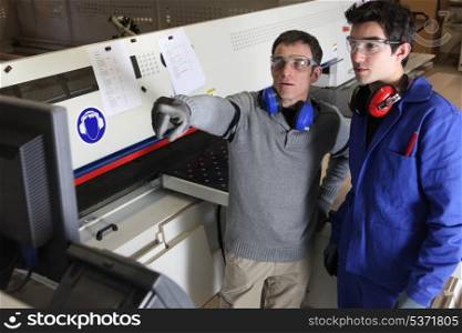 Two men operating factory machine