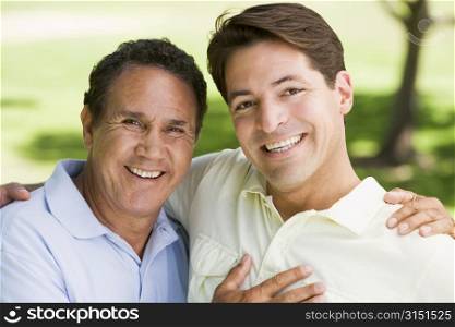 Two men outdoors embracing and smiling