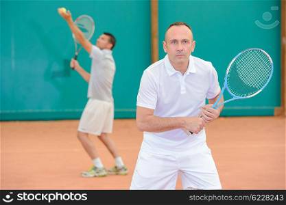 Two men playing doubles tennis
