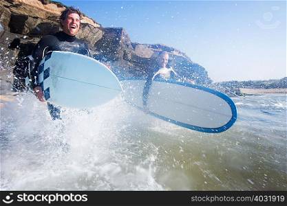 Two men running into the water with surf
