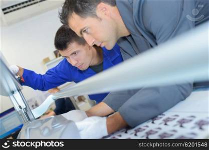 Two men setting up professional printing machine