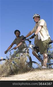 Two men stand with mountainbikes on hilltop