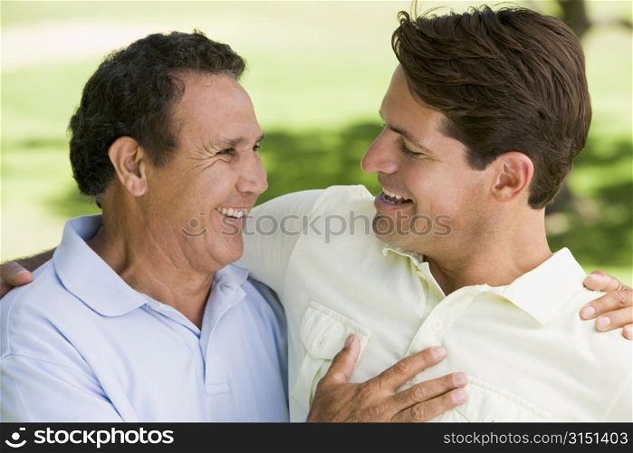 Two men standing outdoors bonding and smiling