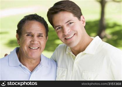 Two men standing outdoors smiling