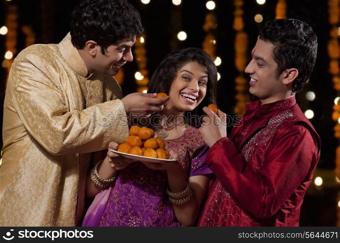 Two men tempting woman to eat sweets