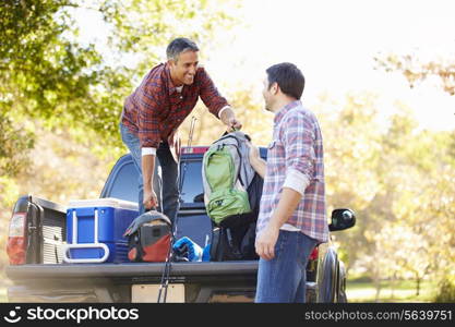 Two Men Unpacking Pick Up Truck On Camping Holiday